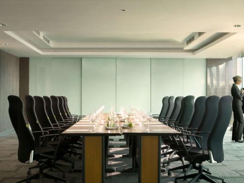 a long table with chairs and wine glasses on it at Novotel Bangka Hotel & Convention Center in Pangkalpinang