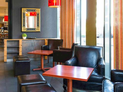 a restaurant with leather chairs and tables and a mirror at Ibis Styles Lyon Centre - Gare Part Dieu in Lyon