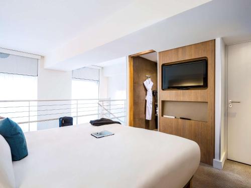 une chambre d'hôtel avec un lit et une télévision à écran plat dans l'établissement Novotel SPA Rennes Centre Gare, à Rennes