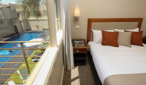 a bedroom with a bed and a balcony with a pool at Quality Hotel Mildura Grand in Mildura