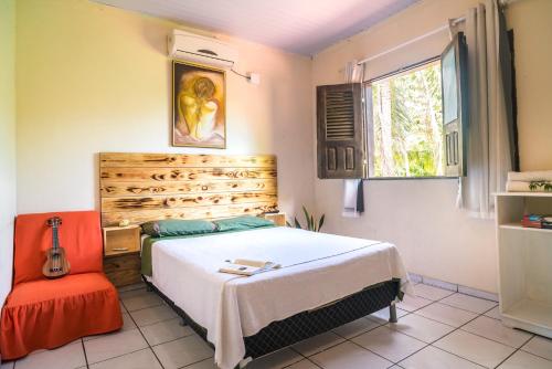 a bedroom with a bed and a orange chair at Casa Vilar Rio Temporada Barreirinhas Lencois Maranhenses in Barreirinhas