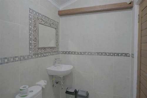 a white bathroom with a sink and a mirror at Jero di Bisma Hostel in Ubud