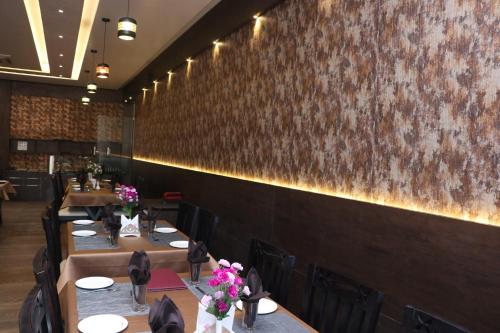 a dining room with tables and flowers on the wall at THE GRAND ASTORIA SOMANTH by Shivalaya Darshanam in Somnath