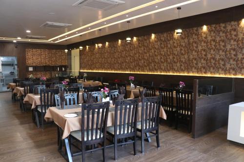 a dining room with tables and chairs at a restaurant at THE GRAND ASTORIA SOMANTH by Shivalaya Darshanam in Somnath