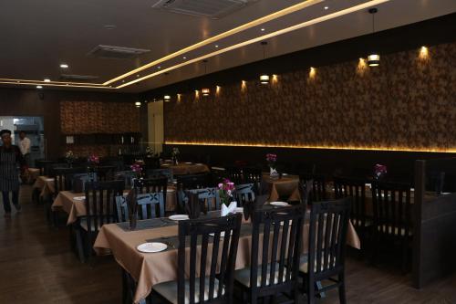 a dining room with tables and chairs in a restaurant at THE GRAND ASTORIA SOMANTH by Shivalaya Darshanam in Somnath