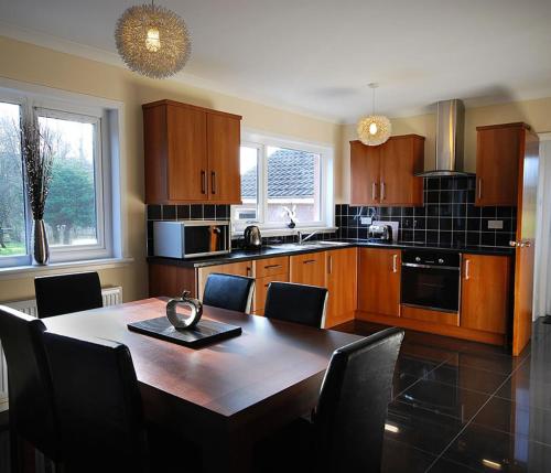 a kitchen with a wooden table and chairs and a tableasteryasteryasteryasteryastery at Clover Holidays - Cliff View in Perth