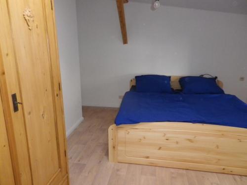 ein Schlafzimmer mit einem Holzbett mit blauen Kissen in der Unterkunft Alte Malztenne im Herzen der Schorfheide in Golzow