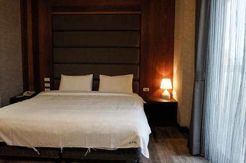 a bedroom with a large bed and a lamp on a table at 晶緻麗景-花蓮火車站正對面 附近有大型收費停車場 in Hualien City