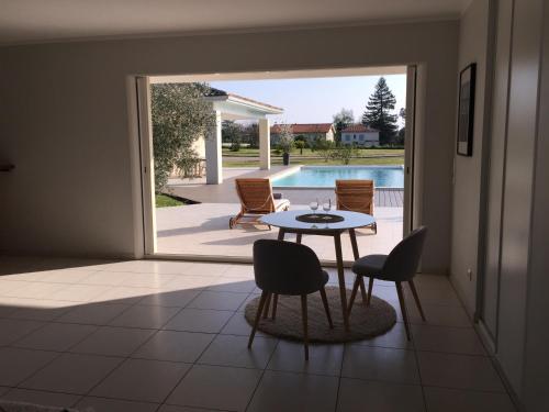 a living room with a table and chairs and a pool at Chambre d'hôtes Ama in Pompignac