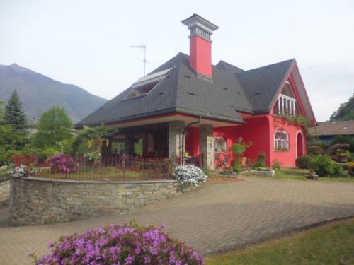 a red house with a black roof and a stone wall at A casa di Lara in Beura