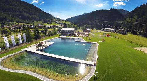 einen Blick über einen großen Pool auf einem grünen Feld in der Unterkunft Alpine Lodge Klösterle am Arlberg in Klösterle am Arlberg