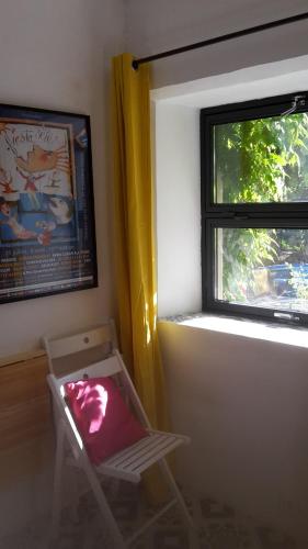 ein Zimmer mit einem Stuhl vor einem Fenster in der Unterkunft Caraussane caractère terrasse sur jardin et wifi via fibre en coeur de ville in Sète