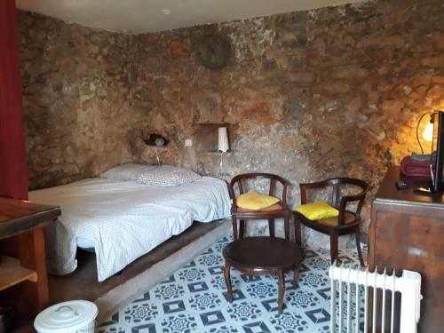 1 Schlafzimmer mit einem Bett, 2 Stühlen und einem Tisch in der Unterkunft Caraussane caractère terrasse sur jardin et wifi via fibre en coeur de ville in Sète
