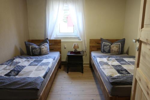 twee bedden in een kleine kamer met een raam bij Ferienwohnungen Kleiner Kuhstall in Kurort Gohrisch