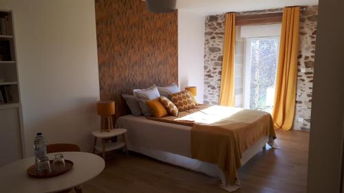 1 dormitorio con cama, mesa y ventana en Chambres d'hôtes de Campagnet, en Moyrazès