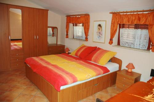 a bedroom with a bed with orange and yellow sheets at Apartments Judit in Tar