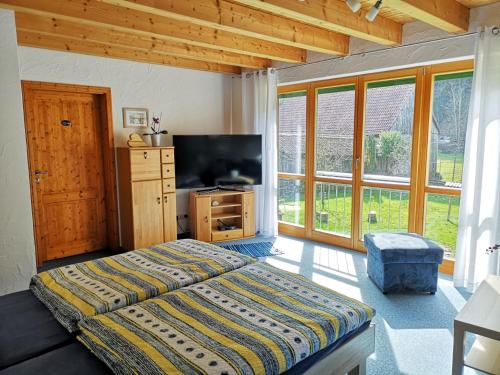 um quarto com uma cama, uma televisão e janelas em Sinnglück em Obersinn