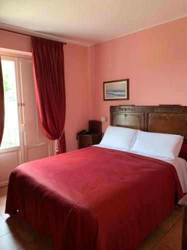 a bedroom with a bed with red sheets and a window at Mongalletto in Castellinaldo