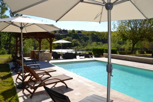 une piscine avec des chaises et des parasols à côté d'une piscine dans l'établissement La noyeraie du port d'enveaux, à Saint-Vincent-de-Cosse