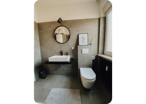 ein Badezimmer mit einem Waschbecken, einem WC und einem Spiegel in der Unterkunft Attraktive 3-Zimmerwohnung - Zentrum Würzburg & nähe Bahnhof in Würzburg