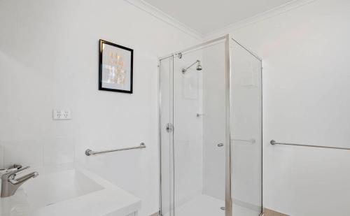 a white bathroom with a shower and a sink at Geelong Serviced Apartments in Geelong