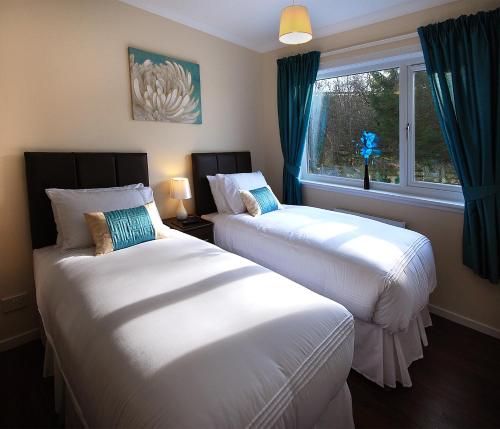 two beds in a room with a window at Clover Holidays - Cliff View in Perth