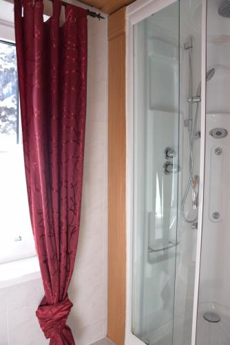 cortina roja en el baño con ducha en Gasthaus Pension Marienhof, en Wald im Pinzgau