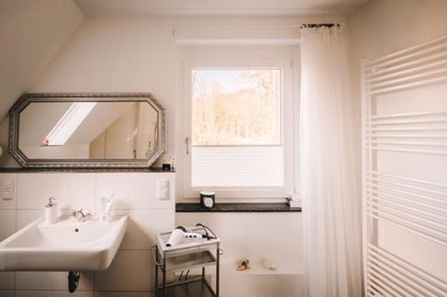 a bathroom with a sink and a mirror and a window at Ferienwohnung am Berg in Lengerich