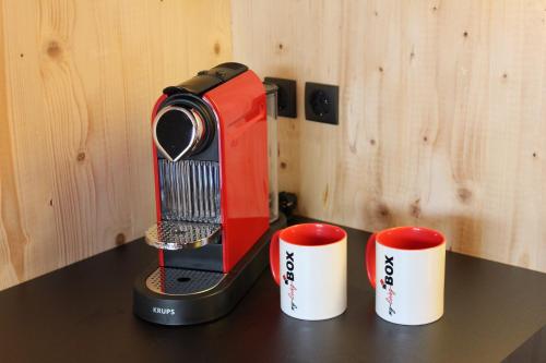 ein roter und schwarzer Toaster auf einem Tisch mit zwei Tassen in der Unterkunft Glück Holiday DB in Uffenheim