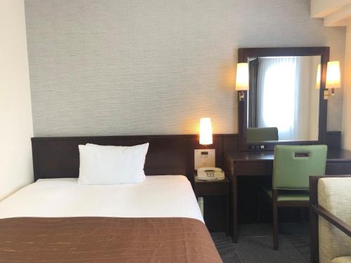 a hotel room with a bed and a desk and a television at Hotel Hokke Club Hakodate in Hakodate