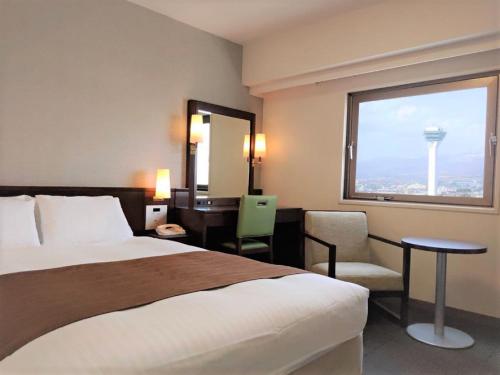 a hotel room with a bed and a desk and a window at Hotel Hokke Club Hakodate in Hakodate