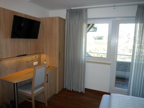 a room with a desk with a television and a window at Hotel - Restaurant Veldscholten in Lingen