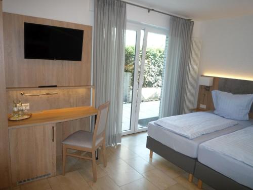 a bedroom with a bed and a desk with a television at Hotel - Restaurant Veldscholten in Lingen