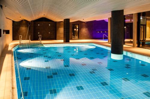 a large swimming pool with blue tiles in a building at Spa Hotel Amsee in Waren
