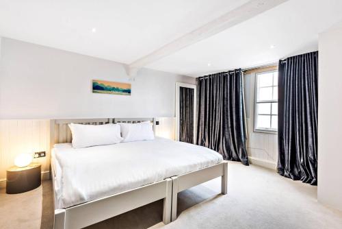 um quarto com uma cama branca e uma janela em Modern, Chic 3BR Townhouse in Central Oxford em Oxford