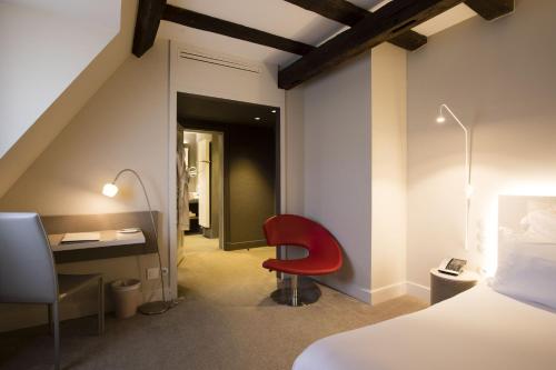 a bedroom with a red chair and a desk at Relais & Châteaux La Maison Des Têtes in Colmar