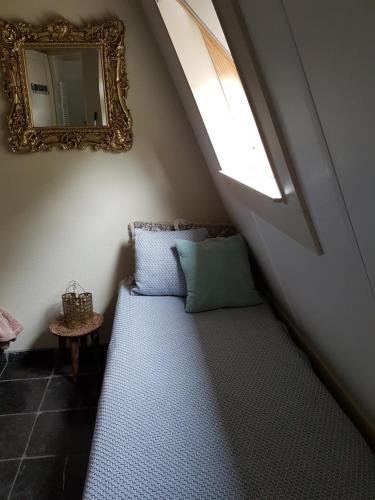 a bed in a room with a window and a mirror at B&B de Remketting in Slijk-Ewijk