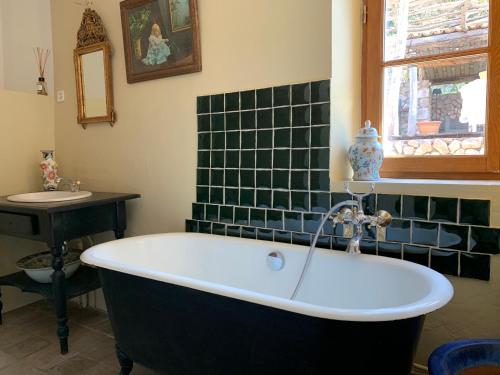 a bath tub in a bathroom with green tiles at Mymoustiers in Moustiers-Sainte-Marie