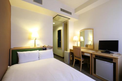 een hotelkamer met een bed en een televisie bij Smile Hotel Nagoya Shinkansenguchi in Nagoya