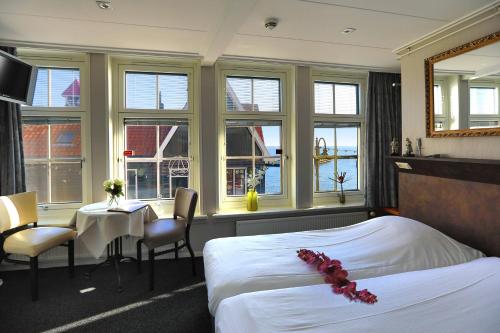 フォーレンダムにあるHotel Cafe Restaurant Van Den Hogenのベッド、テーブル、椅子が備わるホテルルームです。