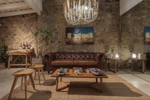 una sala de estar con un sofá de cuero marrón y mesas. en Charco Hotel, en Colonia del Sacramento