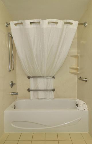 a white bath tub with a shower curtain and towels at Country Inn & Suites by Radisson, Jacksonville, FL in Jacksonville