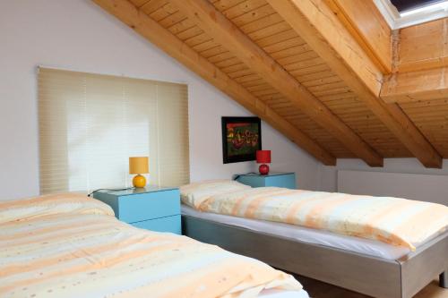 two beds in a bedroom with a wooden ceiling at Artist Apartments & Hotel Garni in Zermatt