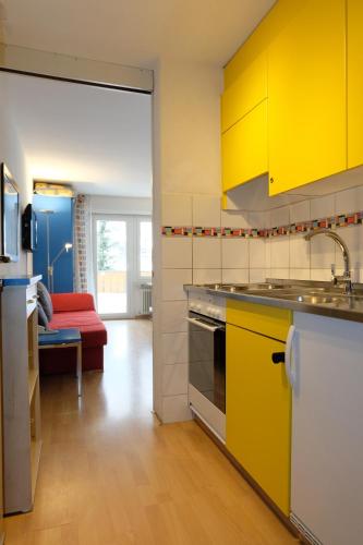 a kitchen with yellow cabinets and a red couch at Artist Apartments & Hotel Garni in Zermatt