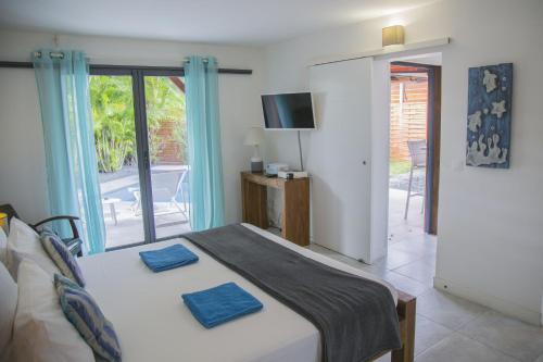 a bedroom with a bed with two blue pillows on it at Fleurs de canne piscines privées in Le Moule