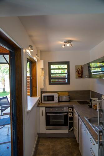 a small kitchen with a stove and a sink at Fleurs de canne piscines privées in Le Moule
