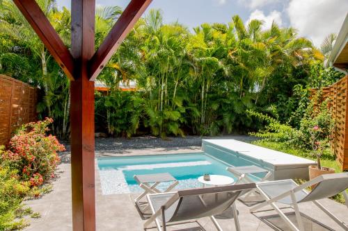 a patio with a pool and chairs and a table at Fleurs de canne piscines privées in Le Moule