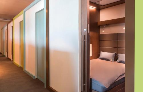 um pequeno quarto com uma cama e um closet em sleep 'n fly Sleep Lounge, SOUTH Node - TRANSIT ONLY em Doha