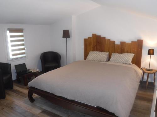 a bedroom with a large bed with a wooden headboard at La Maisonnette de l'échappée verte. in Albi