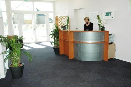 a woman sitting at a desk in an office at Entre le Pont 9 et l'Eveque , Les Hauts de Honfleur, Piscine, WIFI et Parking gratuits in Équemauville